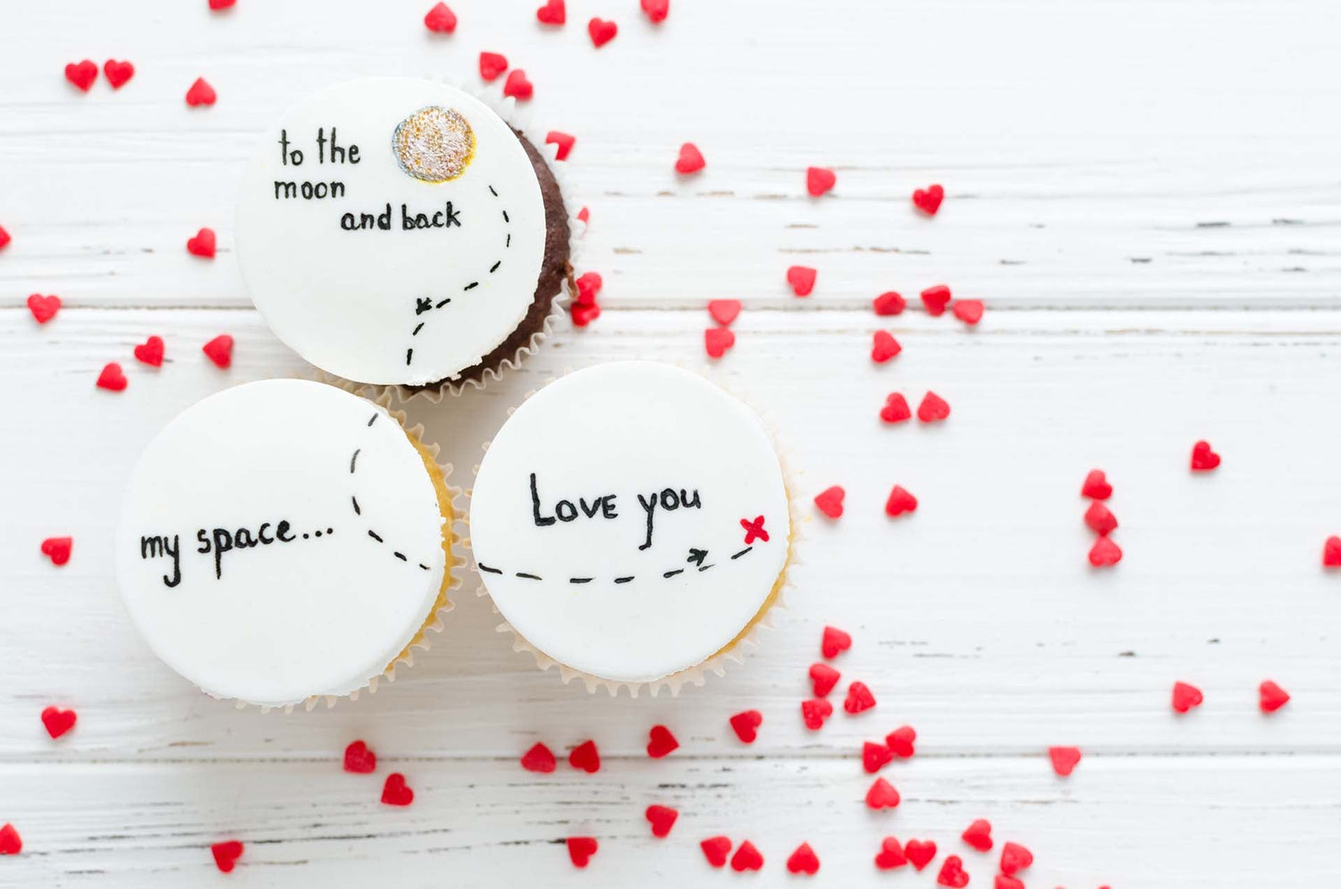 Drei Cupcakes mit bedruckten Esspapier-Auflegern und roten Herzen