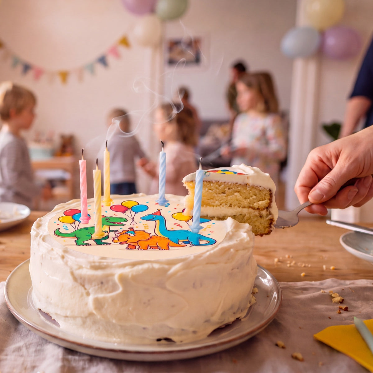 Bunte Dino-Fototorte mit Kerzen beim Anschnitt einer Geburtstagsparty